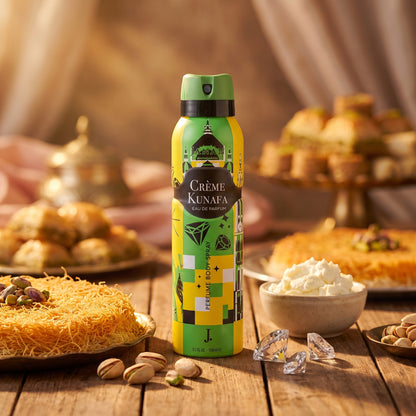 A bottle of Crème Kunafa pastry cream stands on a wooden table surrounded by pastries, pistachios, and whipped cream in a warm, styled setting.